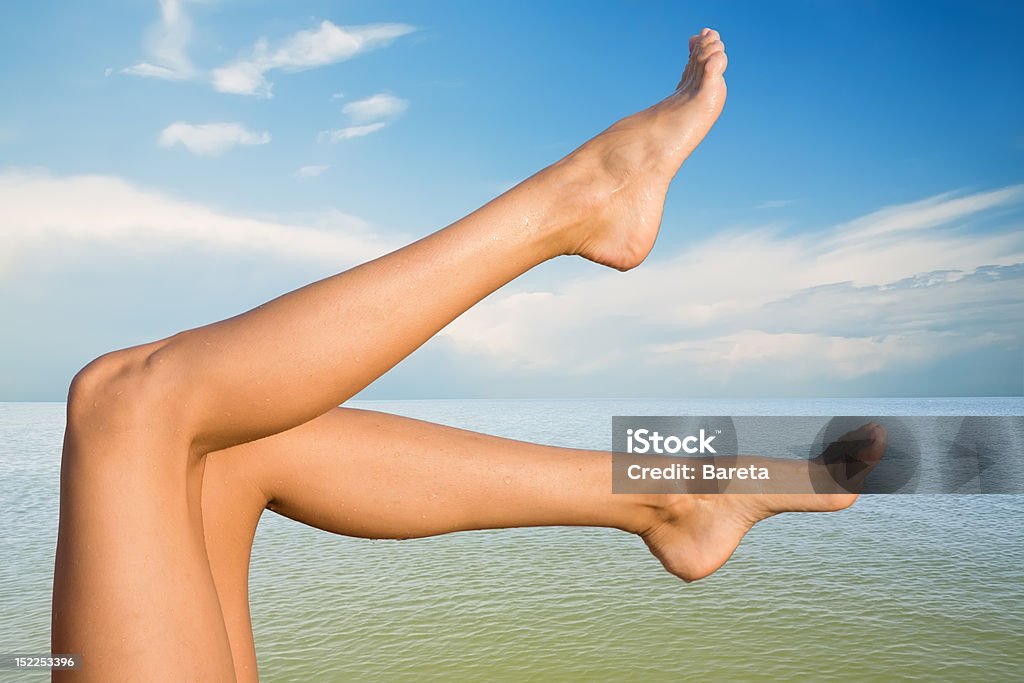 Beach Picture of beautiful female legs on sky background Adult Stock Photo