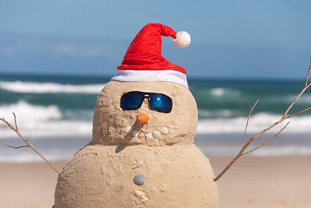 boneco de neve feito de areia com chapéu do pai natal - christmas beach sun tropical climate imagens e fotografias de stock