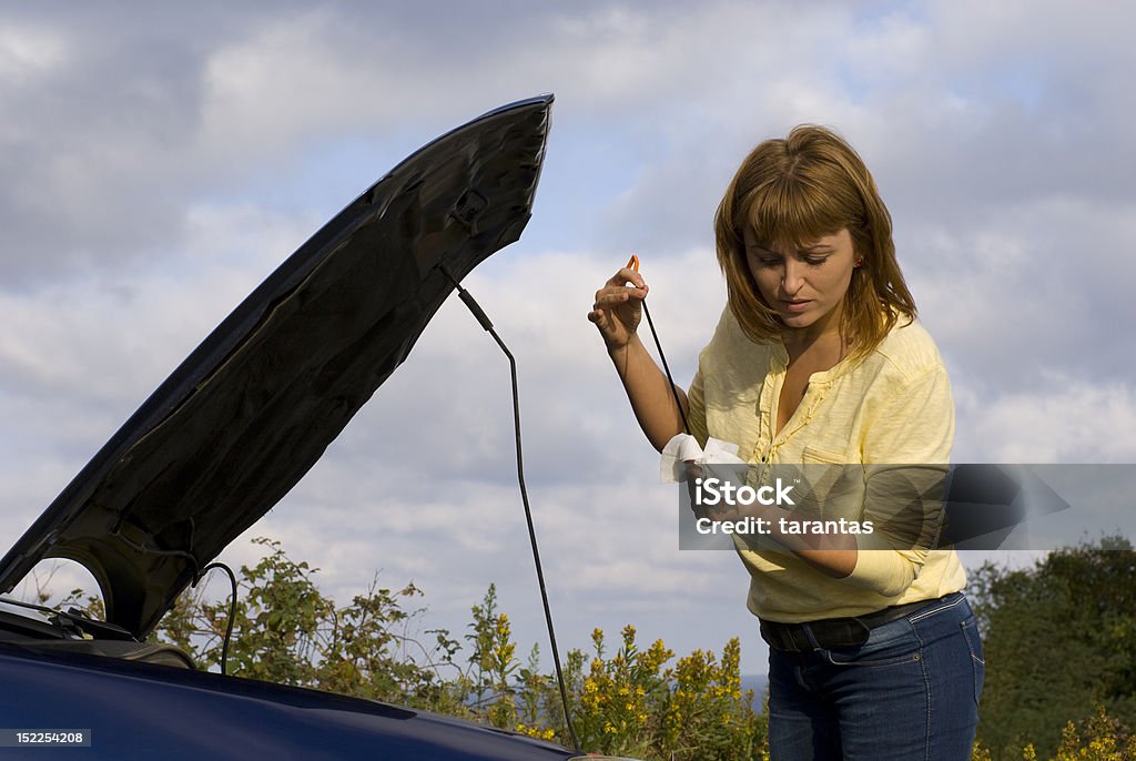 checking engine oil young woman checking engine oil level of her car Accidents and Disasters Stock Photo