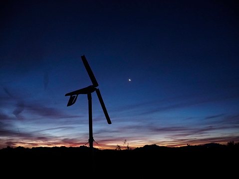 Wind turbine set against a mostly dark sky