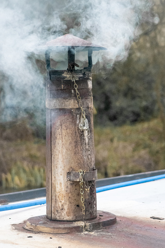 Smoke coming out of a canal ( narrow ) boat chimney on a cold winters afternoon along the Thrupp Canal in Oxfordshire.