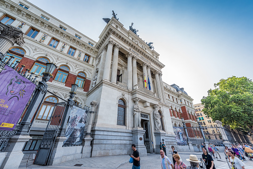 Madrid, Spain - June 27, 2023: Pedestrians and tourists walking in front of the beautiful Palacio de Fomento building, in Madrid. It is currently the headquarters of the Spanish Ministry of Agriculture, Fisheries and Food.