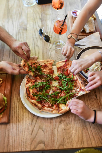 istock Friends Tearing Pieces Off Pizza While Enjoying Dinner In Restaurant 1522582046
