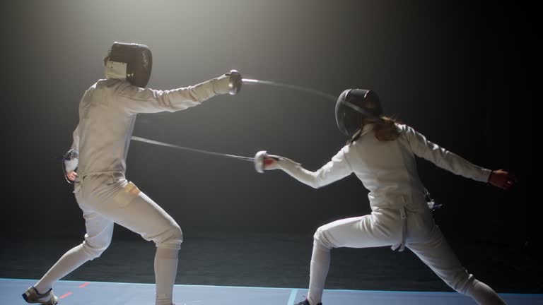 Two fencers bowing and clashing in combat with foil sabre swords. Attacking and landing a direct hit timelapse