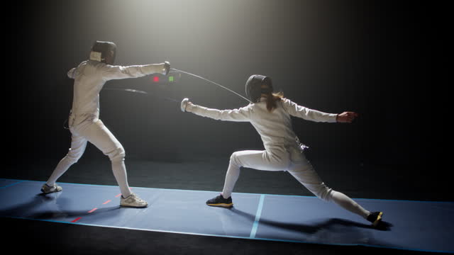 Two fencers bowing and clashing in combat with foil sabre swords. Attacking and ducking