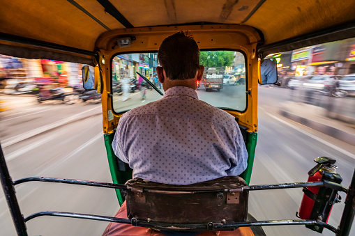 Indian man drives auto rickshaw (tuk-tuk) on streets of Jodhpur in Rajasthan, India.