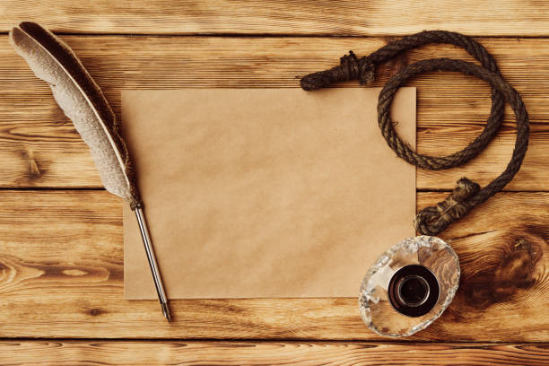 istock Old paper on brown wood background with feather 1522753700