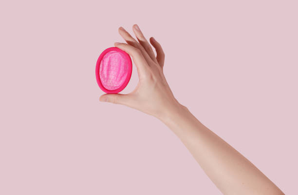 Female hand with reusable menstrual disc on pink background stock photo