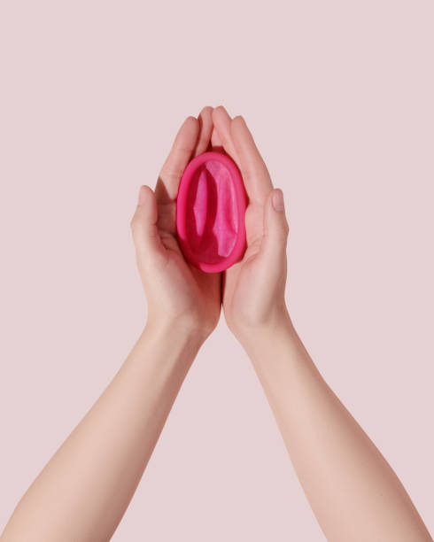 Female hands with reusable menstrual disc on pink background stock photo