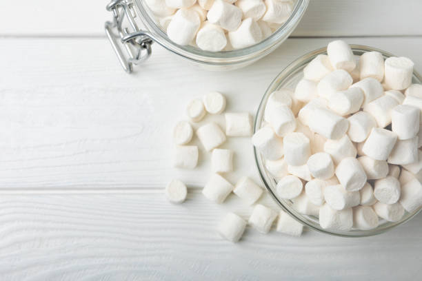 Loose white marshmallows on white texture wood.Sweets and snacks for a snack.Chewy candy close-up.Copy space.Place for text.