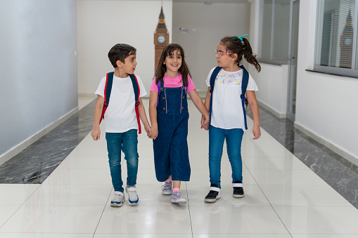 School kids run holding hands in corridor