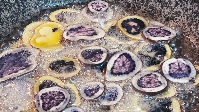 Purple Peruvian potato chips cooking on a pan