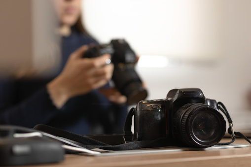 One camera. Blurred background of woman working on his other camera. Photography day concept.
