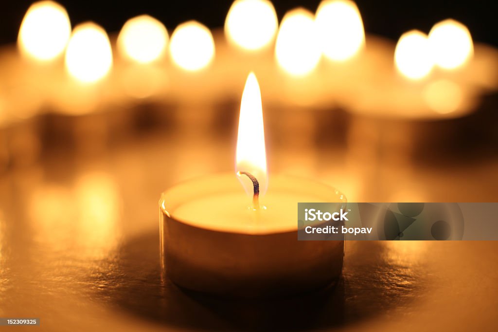 Candle in front of a group of candles a closeup of a circular candles in dark Candlelight Stock Photo