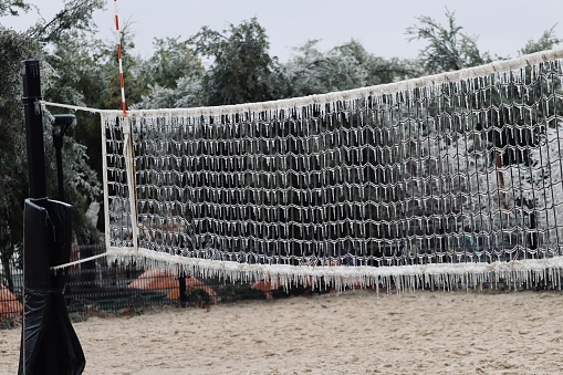 A strong winter storm left a layer of accumulated ice and icicles on a public park volleyball net.