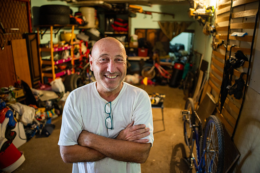 Portrait of senior Caucasian man, looking at his messy garage, but with a positive attitude