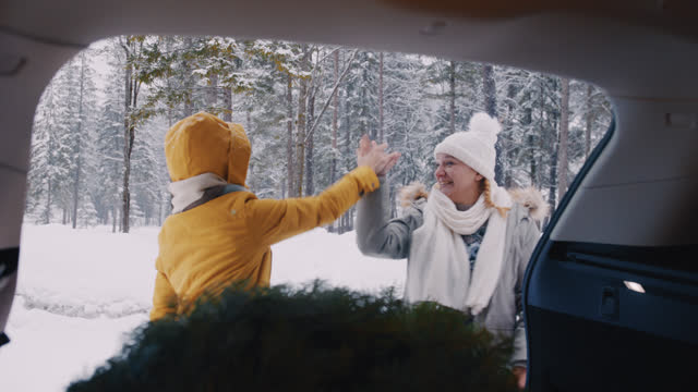 SLO MO Two women gives a high five to each other after loading a Christmas tree