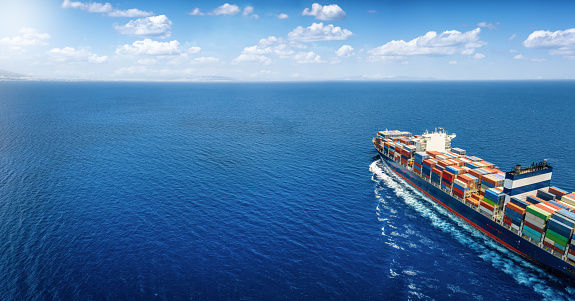 Aerial view of a large cargo ship carrying containers for import and export, business logistic and transportation in open sea with copy space