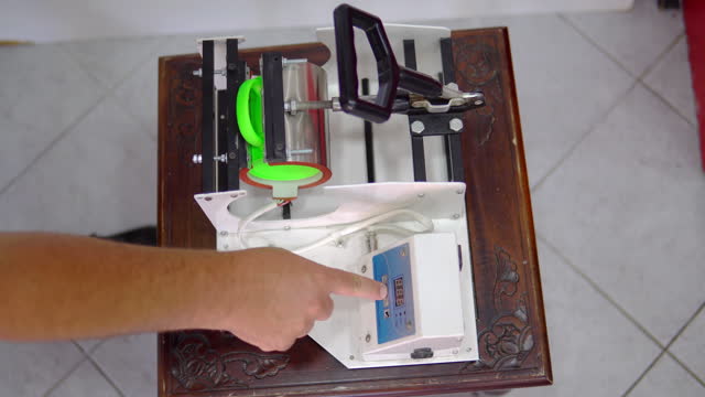 Man making thermal transfer print on green coffee mug, cup print concept