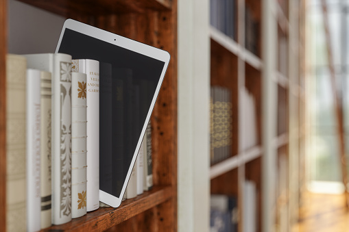 Electronic Library. Close-up View Of Digital Tablet On Bookshelf
