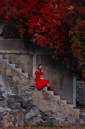 Pensive girl in the stairs wearing a romantic red dress