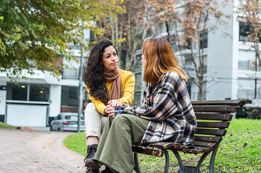 Close-up of relaxed Hispanic teenagers sitting together outside school and going over homework before class begins.