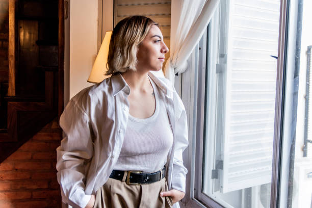 istock Young woman contemplating while look to a window at home 1523376010