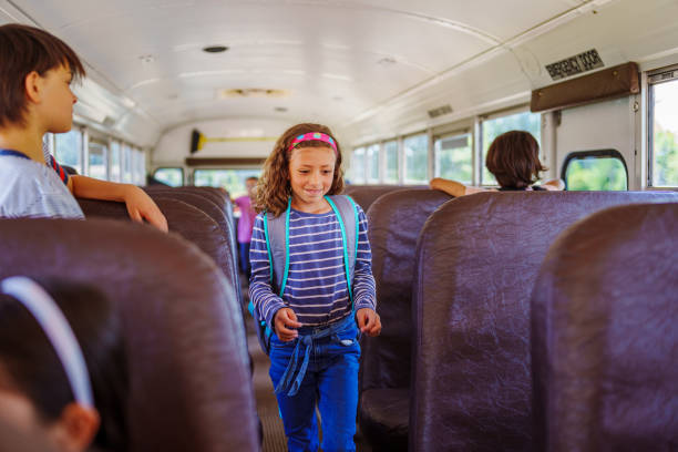 Elementary age girl walking down aisle of school bus