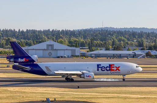 Portland, Oregon, USA - June 10, 2023: Smoke comes off the front wheels as this FedEx Express MD-11 touches down at Portland International Airport.