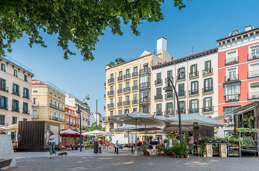 Madrid, Spain - June 27, 2023: View of some neighbors passing through the quiet and traditional square of Tirso de Molina in Madrid. The square has its existence since the year 1840. It is named after Tirso de Molina, a 17th century Spanish playwright who has a statue dedicated to it.