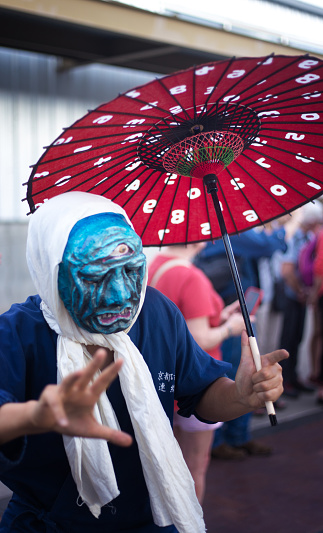 Santa Fe, NM: A Japanese artist wears a traditional mask at the Folk Art procession at the Santa Fe Railyard plaza. The procession kicks off the annual International Folk Art Market (IFAM), where folk artists from over 50 countries participate.