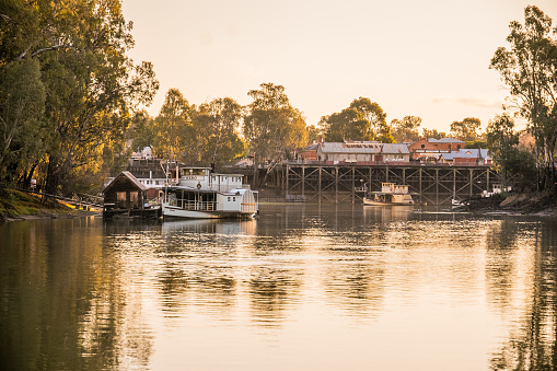 Paddle Steamer on the Murray River at Echuca on the Victorian New South Wales Border, in picture is paddle steamer Hero at sunset, moored to a little wooden jetty with a wooden jetty house,  paddle steamer on the Murray River at sunset,