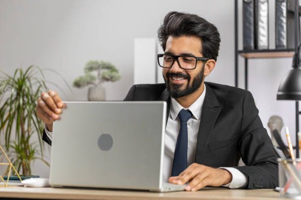istock Indian business man freelancer at office, start working on laptop computer, sends online messages 1523654957