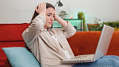 Pretty young woman use laptop surprised by bad news, fortune loss, fail, lottery results at home