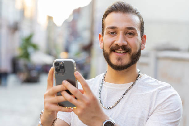 istock Young man use smartphone typing text messages browsing internet finishing work looking at camera 1523684948