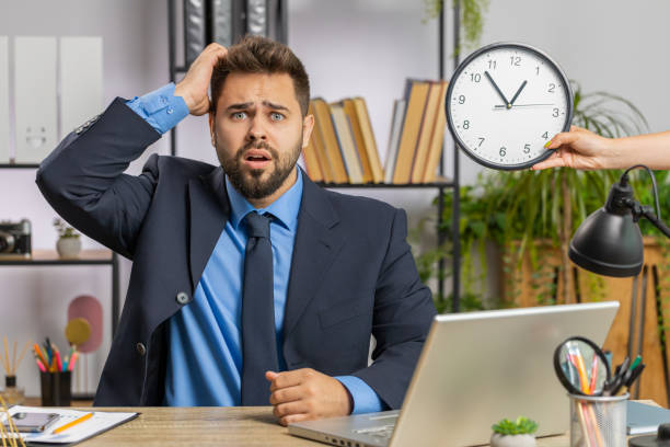 Young businessman with anxiety checking time on clock, running late to work being in delay deadline Caucasian businessman working on office laptop with anxiety checking time on clock running late to work being in delay deadline. Manager freelancer man looking at hour, minutes worrying to be punctual wasting time stock pictures, royalty-free photos & images