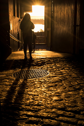 Seattle, USA - Feb 1, 2023: Long shadows of travelers at Pike Place Market off Post alley and the Gum Wall just before sunset.