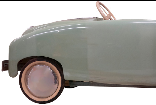 Close up detail of the front end of a mint green MFA pedal car with shiny round hubcaps, a vintage toy for children made in France. Isolated on white with clipping path