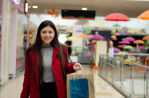 Young beautiful woman with some shopping bags walking in the mall. Consumerism, shopping, lifestyle concept stock photo