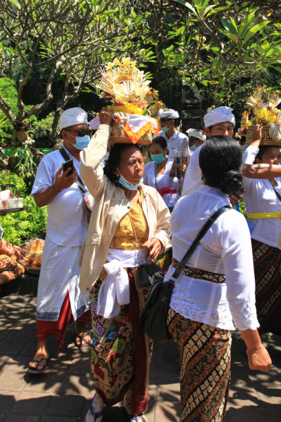 cérémonie balinaise au temple pura goa lawah ou goa lawah dans l’est de bali avec des gens portant des vêtements traditionnels, kebaya, batik sarongs et portant des offrandes sur la tête et avec des hommes portant des chapeaux udeng. - pura goa lawah photos et images de collection