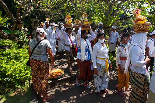 March 15th, 2022 - Goa Lawah, Bali, Indonesia.\nBalinese ceremony at Pura Goa Lawah or Goa Lawah temple in East Bali with people wearing traditional dress, kebaya, batik sarongs and carrying offerings on their heads and with men wearing udeng hats.