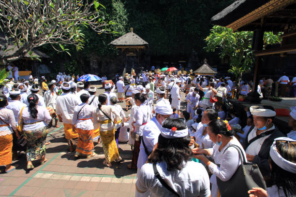 scène à l’intérieur du temple pura goa lawah à klungkung, east bali, indonésie avec de nombreuses personnes vêtues de vêtements traditionnels tels que kebaya et batik sarong avec les hommes portant des couvre-chefs udeng et les femmes avec des fle - pura goa lawah photos et images de collection