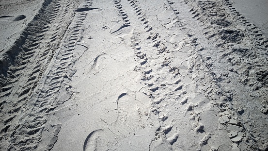 On the ground surface of the white sand beach there are traces of vehicles