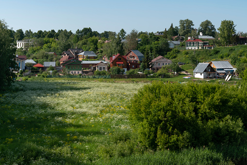 View of traditional wooden houses on the left bank of the Kamenka River on a sunny summer day, Suzdal, Vladimir region, Russia