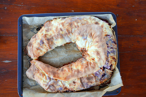 Rolled up the home made cheese, apple strudel stuffed with grated apples, butter, cheese cream  and blueberry, on rolled dough is in baking pan with baking paper. Butter and egg spread is added to the apple strudel.