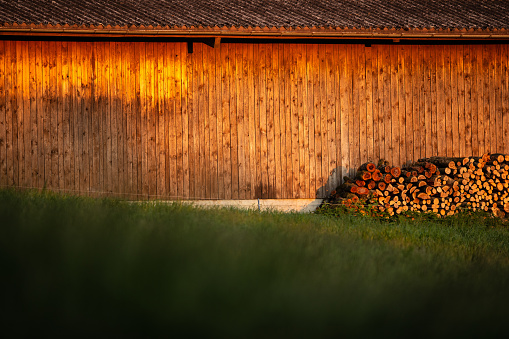 Dusk settles over hillside barn. Evening warm sunlight hitting a wooden barn.
