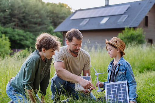 Father and his children standing in front of their house with photovoltaics on the roof.