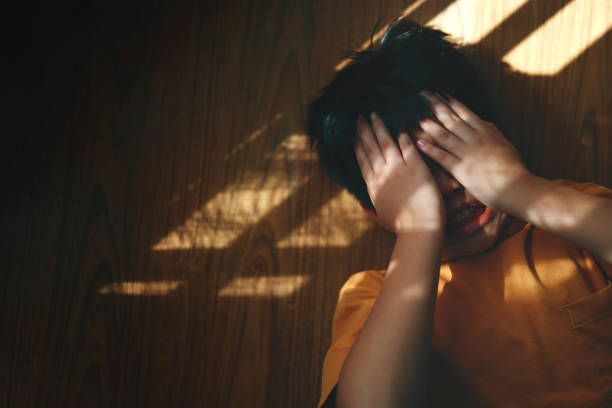 istock An angry and frustrated boy is seen from a top view, covering his face with his hands while lying on the floor 1524468174