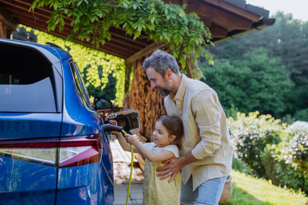 Father with his little daughter charging their electric car. stock photo