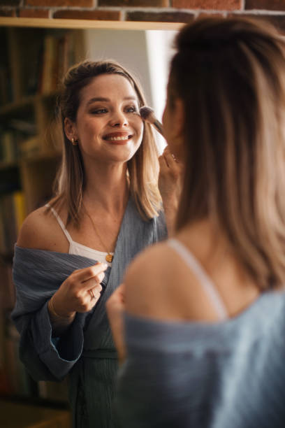 istock Young woman doing her make-up, looking in mirror. 1524478652